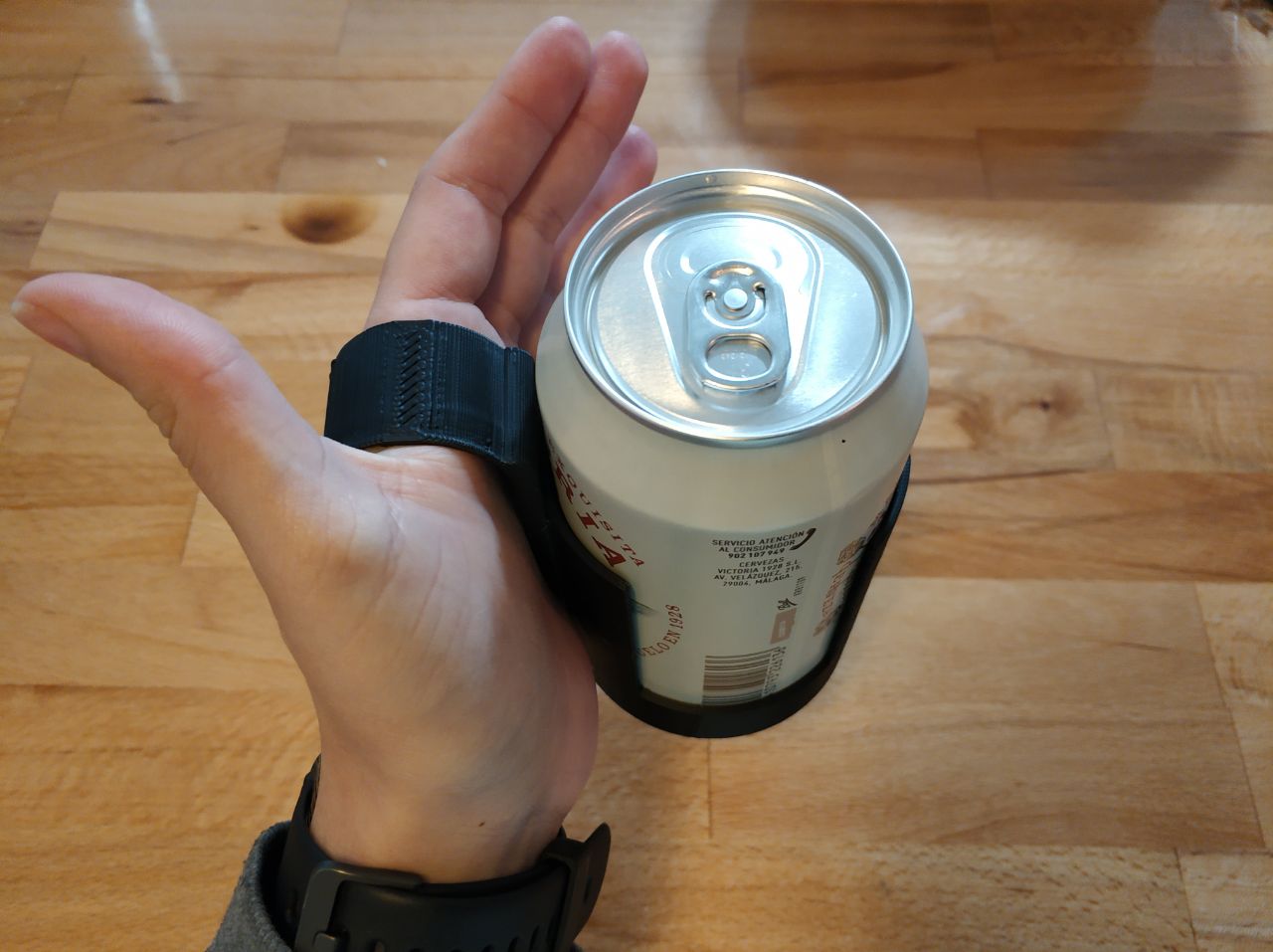 Mano sujetendo una lata de bebida con ayuda de un agarrador adaptado